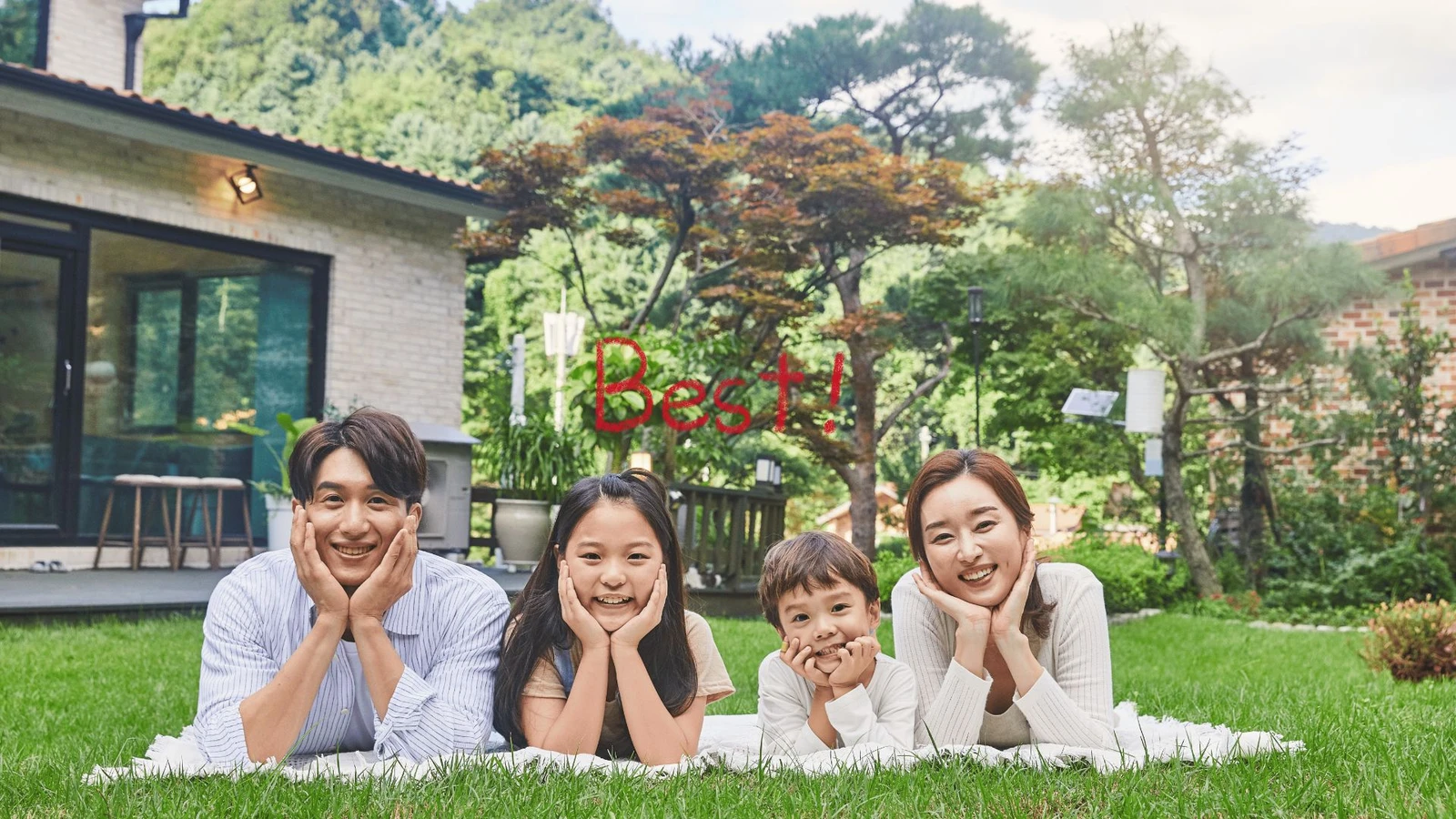 초록 잔디밭 위 하얀 담요에 엎드려 환하게 웃는 네 가족의 행복한 모습. 가족 간 저가 양도 성공으로 얻은 안정과 화목을 보여주는 장면이다.